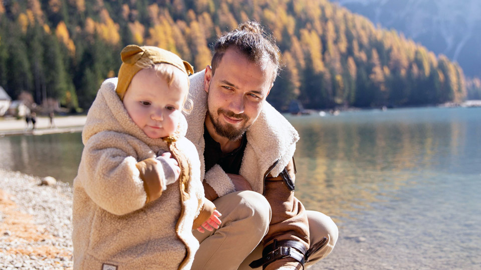 Parent taking toddler for a walk by a lake