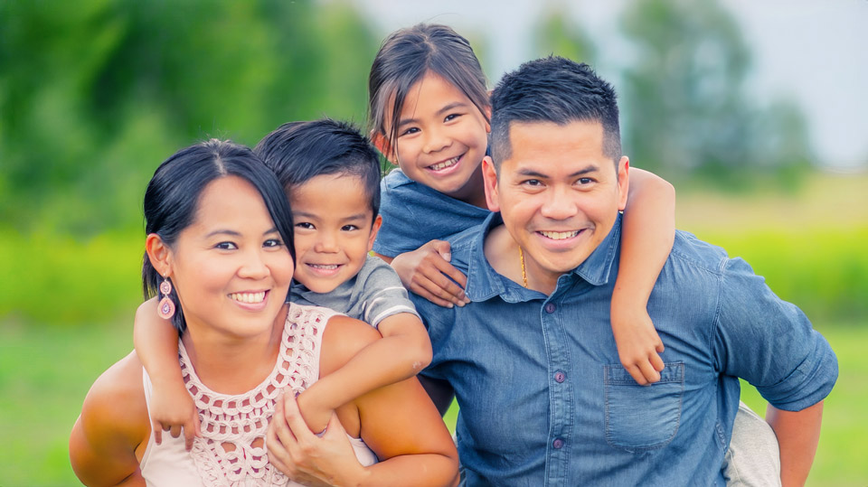 Parents affectionately holding small child on shoulders